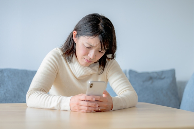 スマホをもってモヤモヤしている女性